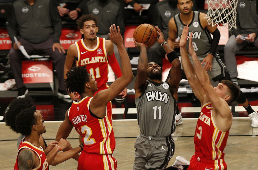 Dec 30, 2020; Brooklyn, New York, USA; Brooklyn Nets guard Kyrie Irving (11) goes up for a shot against Atlanta Hawks forward De'Andre Hunter (12) and guard Bogdan Bogdanovic (13) during the second half at Barclays Center. Mandatory Credit: Andy Marlin-USA TODAY Sports