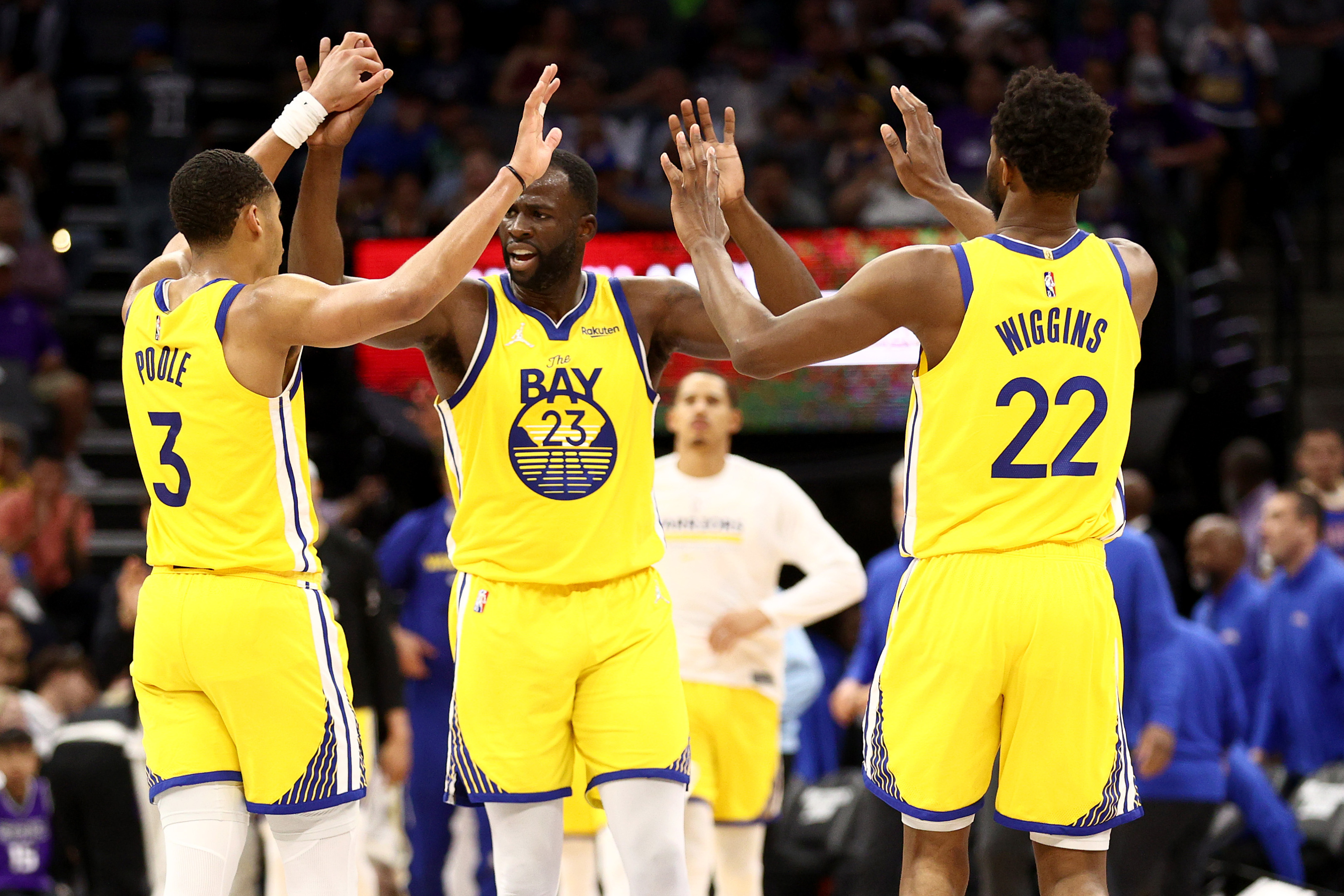 SACRAMENTO, CALIFORNIA - APRIL 03:  Jordan Poole #3, Draymond Green #23 and Andrew Wiggins #22 of the Golden State Warriors high five after the Warriors scored a basket against the Sacramento Kings in the second half at Golden 1 Center on April 03, 2022 in Sacramento, California. NOTE TO USER: User expressly acknowledges and agrees that, by downloading and/or using this photograph, User is consenting to the terms and conditions of the Getty Images License Agreement.  (Photo by Ezra Shaw/Getty Images)